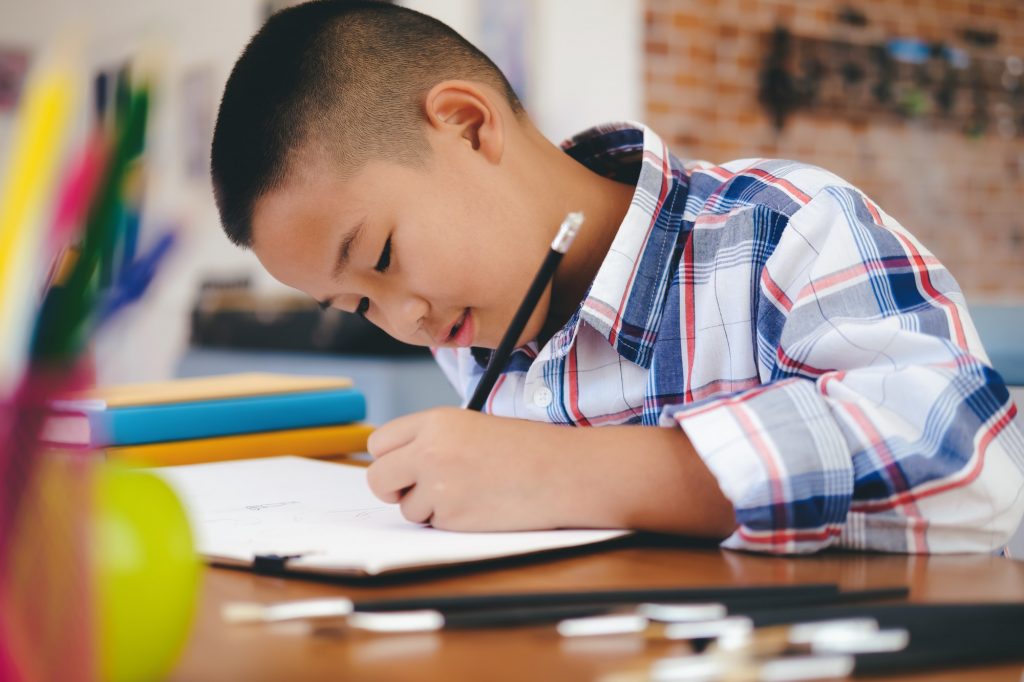 A little boy is busy doing his homework.