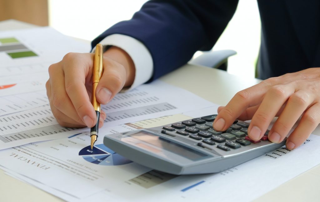 Analysts use calculators and pointers on graphs to assess the fluctuating stock market situation.