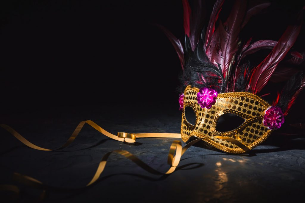 Golden carnival mask with golden ribbon on black background