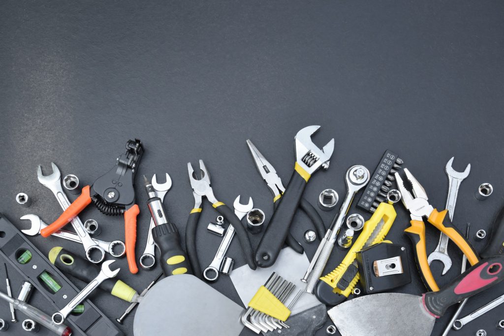 Handyman tool kit on black wooden table. Many wrenches and screwdrivers, pilers and other tools for