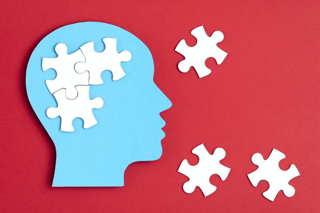 Papercut head with jigsaw puzzle pieces inside. Mental health problems, psychology, memory, logic